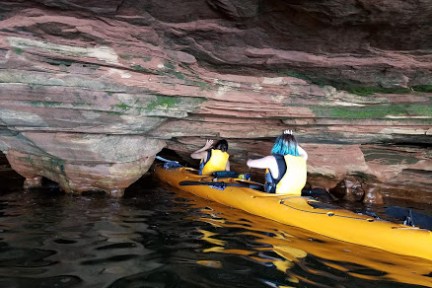 A group of people touching the rocks while in a tandem kayak