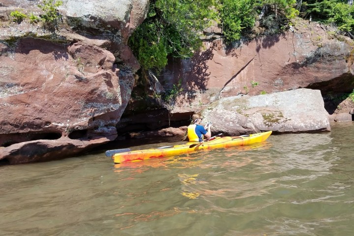 A person in a Kayak near the rocks