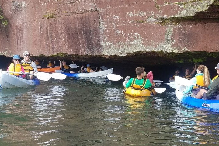 A group kayaking near a rock overhang