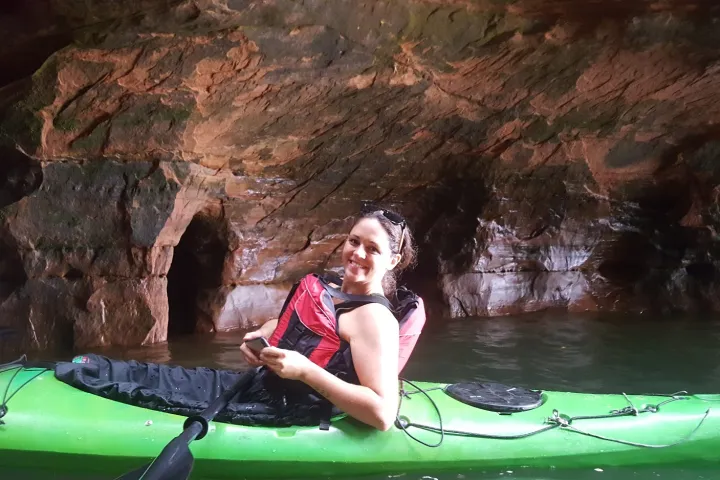A woman in a tandem kayak in a sea cave at Meyers Beach