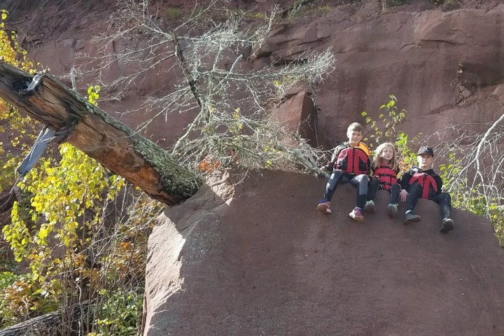 A group of kids sitting on a rock near Red Cliff Caves