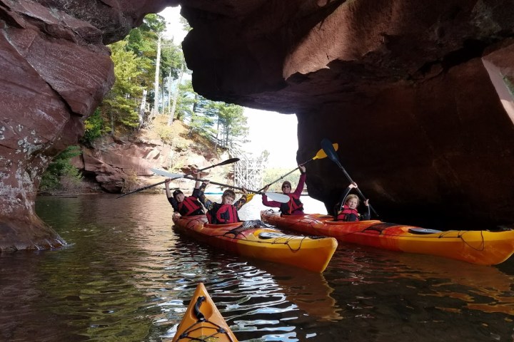 Kayakers holding up their paddles at Red Cliff caves